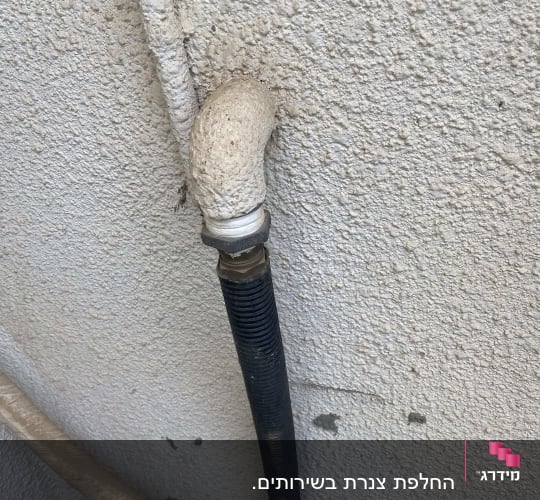 צינור מתכת מחובר לקיר עם חיבור זוויתי